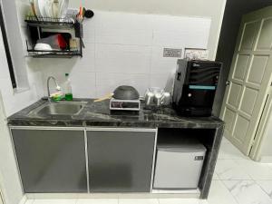 a kitchen counter with a sink and a microwave at Aufa Homestay Pendang in Pendang