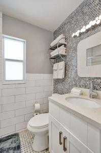 a white bathroom with a toilet and a sink at Art Deco Oasis by Las Olas in Fort Lauderdale