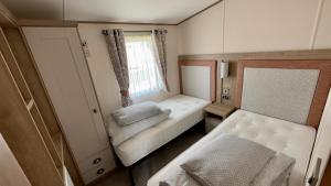 タターズホールにあるLuxury Hotub Lodge with Lake View at Tattershall Lakesのベッドと窓が備わる小さな客室です。