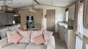 a living room and kitchen with a couch in a caravan at Luxury Hotub Lodge with Lake View at Tattershall Lakes in Tattershall