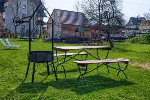 a picnic table and two benches in a park at Apartments Pod Jaworami in Białka Tatrzańska