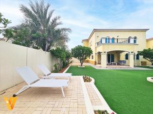un patio con 2 sillas blancas y una casa en Luxury 3BR Private Villa and Elaborate Gardens en Dubái