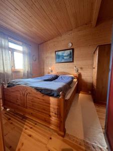 ein Schlafzimmer mit einem Holzbett in einem Zimmer in der Unterkunft Cozy and spacious cabin in Svensby