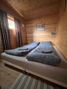 Cozy and spacious cabin في Svensby: غرفة نوم بسريرين في كابينة خشبية