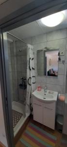 a bathroom with a sink and a shower and a mirror at Apartman Olive grove in Rogoznica