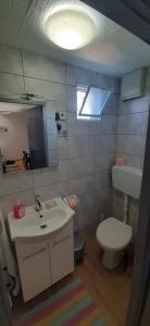 uma casa de banho com um lavatório, um WC e uma luz em Apartman Olive grove em Rogoznica