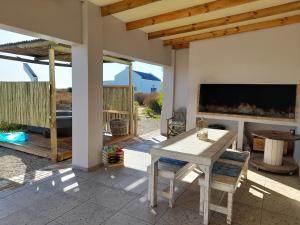 a patio with a table and chairs and a fireplace at Camelot Cottages in Langebaan