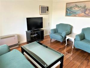 a living room with two blue chairs and a flat screen tv at Easy Self Check-in accomodation in Springvale