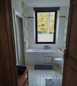 a bathroom with a tub and a toilet and a window at Granny Cottage. in Marchin