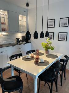 a kitchen with a white table and black chairs at Apartament Szum w Pinea in Pobierowo
