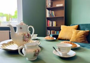 a table with a teapot and cups and plates on it at Apartament Stary Zdrój in Wałbrzych