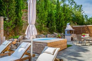 a patio with a hot tub with chairs and an umbrella at Nightingale Villa & Suites Corfu in Gazátika