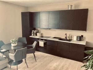 una cucina con armadi neri e tavolo con sedie di Free parking central 2bedrooms with terrace ad Ålesund