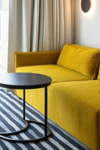 a living room with a yellow couch and a table at GreenPort Apartamenty Kołobrzeg - Dining & SPA in Kołobrzeg