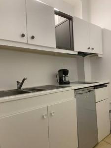 una cocina con armarios blancos y fregadero en Grand Studio indépendant, en Pignan