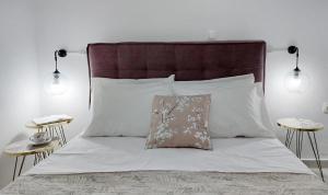 a bed with white sheets and a brown headboard and pillows at Maria's Dream House in Ierapetra