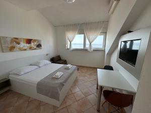 a white bedroom with a bed and a television at Stipe Residence in Podstrana