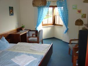 a bedroom with a bed and a desk and a window at Pension Teichblick in Lichtenberg