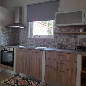 cocina con armarios de madera, fregadero y ventana en Maro Sweet Home en Aigio