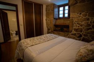 a bedroom with a bed and a stone wall at Casa do Charco Peneda Gerês in Parada