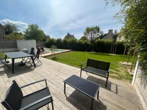 une terrasse en bois avec une table et des chaises ainsi qu'une cour dans l'établissement Charmante maison avec piscine, à Beaussais sur Mer