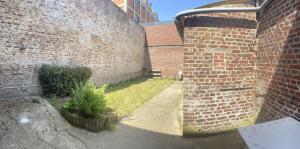 un callejón con una pared de ladrillo y una planta en Maison à 2 pas du centre ville, en Péronne