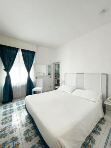 a bedroom with a large white bed and blue curtains at Regina Cristina in Capri