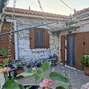 a stone house with wooden shutters and a patio at Afroditi's 2 in Eresos