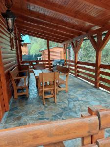 un porche de una cabaña con mesas y sillas de madera en Brvnara Ibar, en Rožaje
