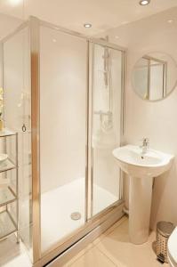 a white bathroom with a shower and a sink at Little Ships overlooking the Royal Harbour in Kent