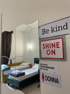 a room with two beds and a sign that says be kind shine on at Grand Cucinetta in Rome