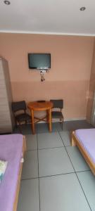 a room with a table and two beds and a tv at NOCLEGI ELA in Sieradz