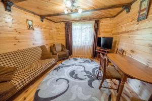 a living room with a couch and a table and a tv at Сосновий Бір, Світязь in Svityazʼ
