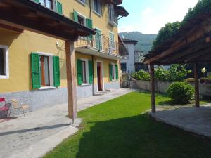 a yard with a building with green shutters at Casa Mimosa - appartamento vacanze sul Lago di Como in Sorico