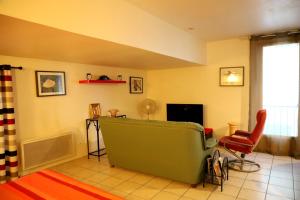 a living room with a green couch and a chair at Mas de Bellegou in Portiragnes