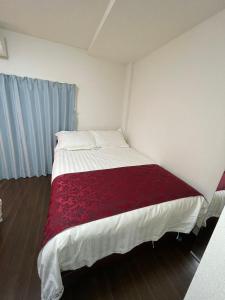 una piccola camera con un letto con una coperta rossa di 竹苑（一戸建て）露天温泉歩い1分間・梅田まで12分・天神橋六町目歩いて7分間 ad Osaka Altre 22 foto