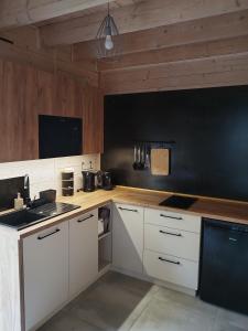 a kitchen with white cabinets and a black wall at SOSNOWY KLIFF in Niechorze