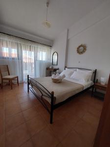 a bedroom with a bed and a chair and a window at El Verde Apartments in Skala