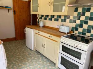 a kitchen with white appliances and green and white tiles at Kings Arms Annex in Steventon