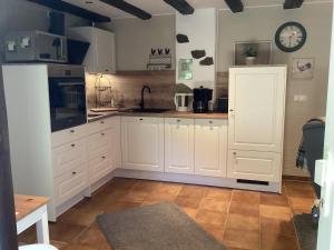 a kitchen with white cabinets and a clock on the wall at Alter Winzerhof in Hatzenport