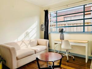 a living room with a couch and a desk at Bay Rd Kids & Pet Friendly Free Parking in Cheltenham