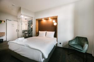 a bedroom with a large bed and a green chair at Travel24 Hotel Leipzig City in Leipzig