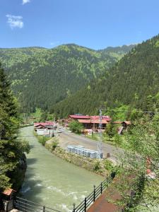 a river in front of a village with a mountain at Uzungol Soylu Hotel in Uzungöl