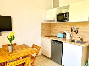 a small kitchen with a table and a microwave at Blue Summer Vibes Apartment for 4P, AC, balcony, parking, beach at 50m, SPA access -4 in La Ciotat