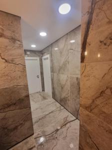 La salle de bains est pourvue de murs en marbre et d'un grand miroir. dans l'établissement הברון baron, à Rishon LeẔiyyon