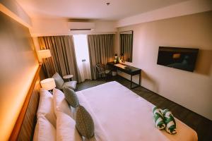 Habitación de hotel con cama y escritorio en The Maximilian Hotel en Ciudad de Cauayán