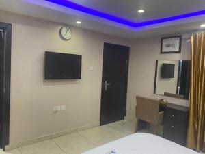 een slaapkamer met een tv aan de muur en een klok bij Studio B, (Studio Apartment) Hillside Gardens in Lagos