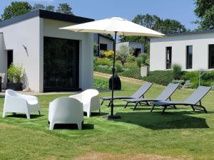 a group of chairs and an umbrella on the grass at Maison d'architecte avec SPA in Concarneau