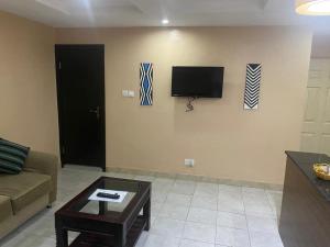 een woonkamer met een bank en een tv aan de muur bij Studio B, (Studio Apartment) Hillside Gardens in Lagos