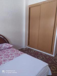 een slaapkamer met een bed en een houten deur bij BOUZNIKA in Bouznika